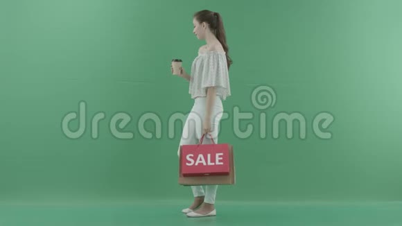 年轻的美女喝着咖啡把袋子放在绿色的屏幕上视频的预览图