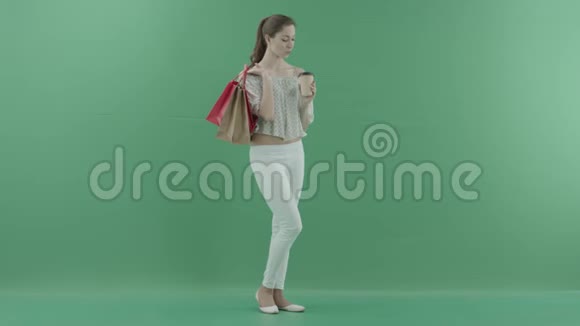 年轻的美女喝着茶把袋子放在绿色的屏幕上视频的预览图