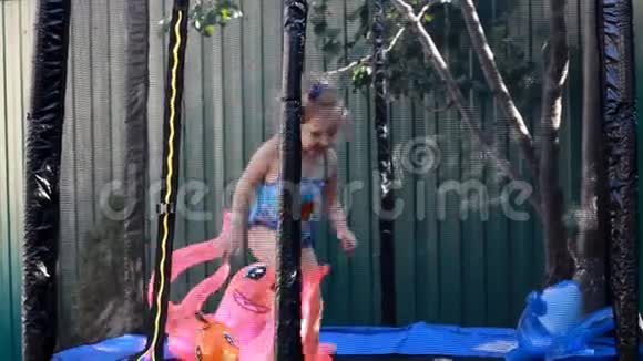 小女孩跳在蹦床上在乡下的房子里玩儿童运动会视频的预览图