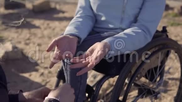 家庭休闲坐在轮椅上的残疾青年妇女与坐在海边的母亲说话抱着她视频的预览图