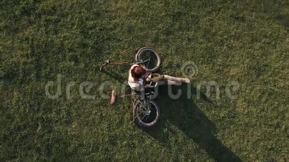 一位骑自行车的女士躺在草地上用手机视频的预览图