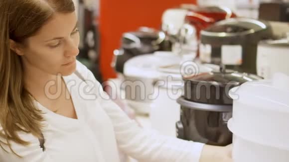 年轻女子在商店买厨房用具去找蒸笼背景白色商品视频的预览图