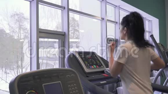 漂亮的黑发女人在跑步机上跑步视频的预览图