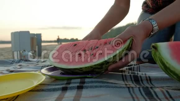 快乐的女孩在海滩上吃西瓜片父亲切西瓜夏天在户外野餐视频的预览图