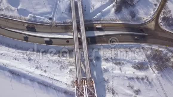 汽车和货车在火车桥下的冬季公路上行驶无人驾驶飞机的视野冬季雪道上的汽车交通视频的预览图