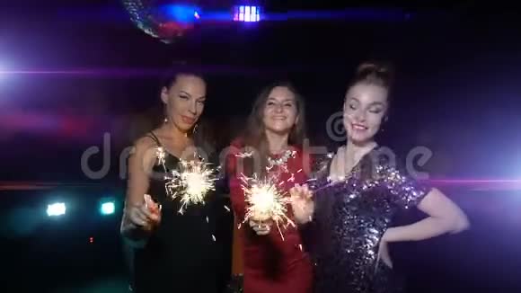 三个女人跳舞玩得开心在新年或圣诞晚会上捧起火花视频的预览图