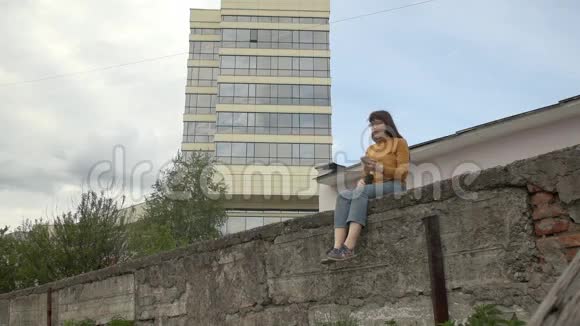 一个女人在屋顶边缘使用电话视频的预览图