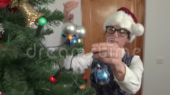 女人把圣诞装饰放在云杉上视频的预览图