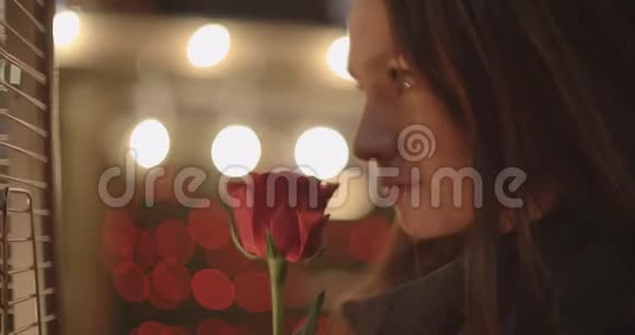 美丽的黑发女孩站在一个城市的红玫瑰视频的预览图