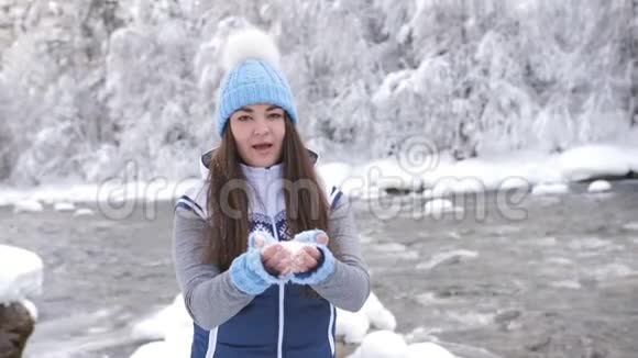 冬天河边的一个女人享受着一个寒冷的早晨把雪扔在自己身上从幸福中旋转视频的预览图