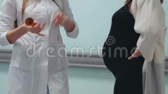一位孕妇走在移植中心的走廊里与穿着白色晨衣的医生交流视频的预览图