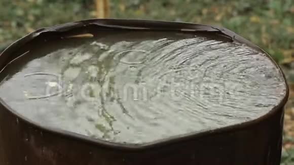 雨水流入一个生锈的旧桶雨滴特写视频的预览图