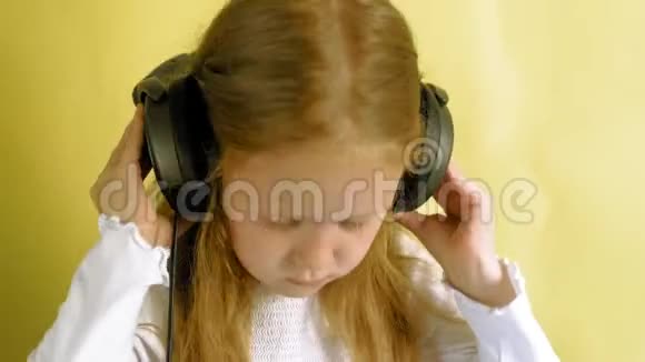 黄色背景上戴着耳机的快乐小女孩特写肖像视频的预览图