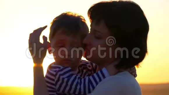 幸福的家庭母亲在夕阳的背景下抱着孩子在麦田里视频的预览图