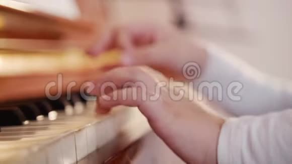 音乐课弹钢琴的女孩把琴键合上孩子的手玩游戏的斜视图视频的预览图