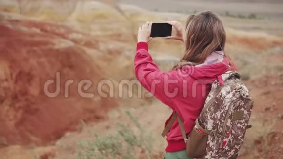女游客在相机智能手机上制作照片红色的山脉和红色的地球就像火星一样视频的预览图