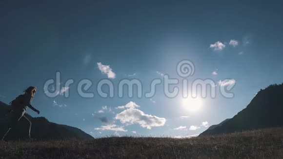 一个旅行者在山峦和天空背景下的剪影那个旅游女孩正沿着山顶走视频的预览图