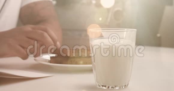 杯子里有牛奶男人手里有饼干把牛奶里的饼干弄湿视频的预览图
