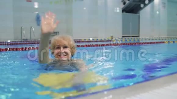漂亮的奶奶挥手在游泳池里游泳视频的预览图