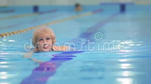 老妇人在蓝色游泳池游泳视频的预览图