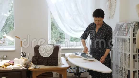 专业的手工师傅在她的房间里熨烫织物手工制作的概念视频的预览图