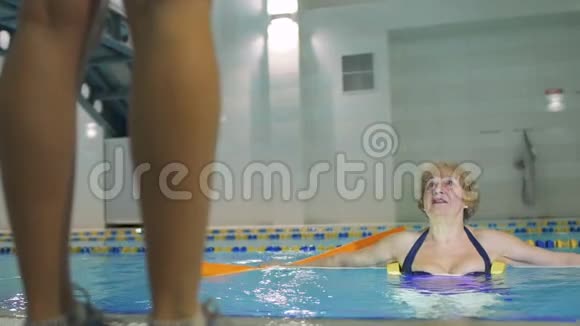 高级妇女和教练一起在游泳池里做运动视频的预览图