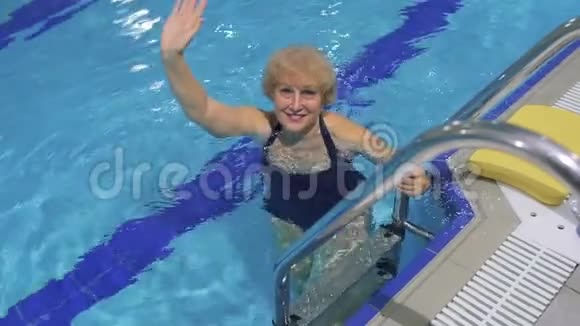 微笑的老妇人在游泳池里挥手视频的预览图
