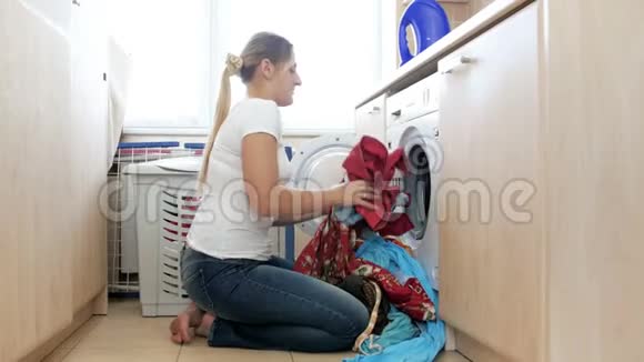 4k镜头微笑的年轻女子装洗衣机开始洗衣视频的预览图