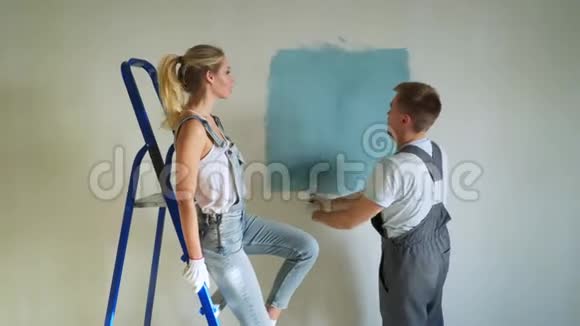 年轻的家庭夫妇用滚筒粉刷公寓或房子里的墙壁视频的预览图