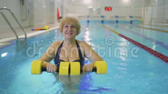 老年妇女在游泳池里用哑铃做运动视频的预览图