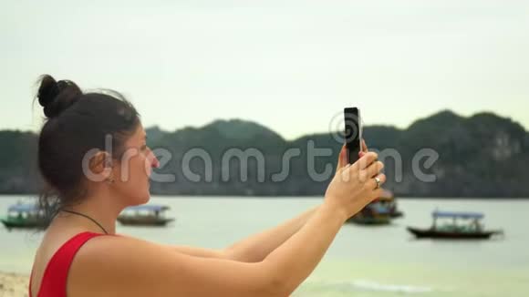 在热带小岛海滩上的女人在智能手机上自拍在岛上的旅行者视频的预览图