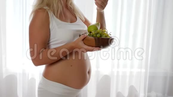 健康怀孕肚子大的孕妇吃葡萄拿着木盘吃水果视频的预览图