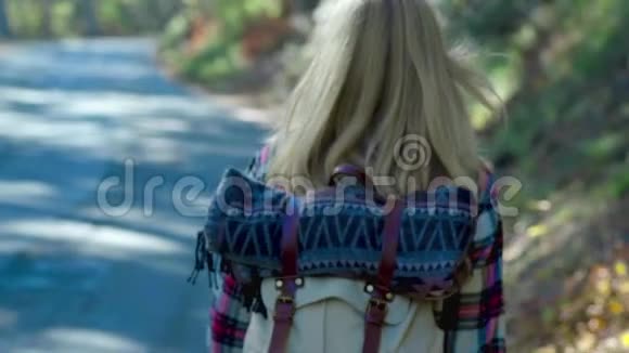 旅行者女人搭便车在森林道路上行走年轻快乐的背包客女人想要搭车开始视频的预览图