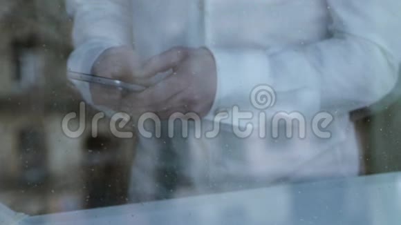 沮丧的离婚男子从智能手机发短信雨点落在窗户玻璃上视频的预览图