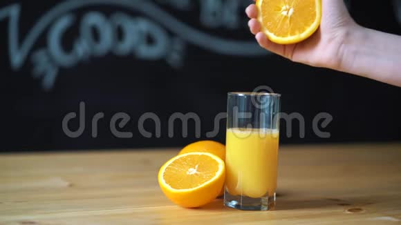手挤橙汁在透明玻璃玻璃在黑色的石板墙上视频的预览图