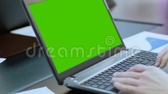 在带有绿色屏幕的笔记本电脑上工作的人使用触摸板滚动网页视频的预览图