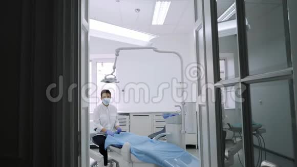 牙医邀请病人坐下来病人坐在蓝色牙医椅上视频的预览图