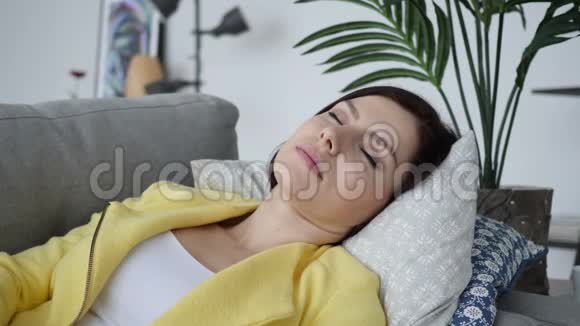 睡懒觉的年轻女子躺在家里的沙发上视频的预览图