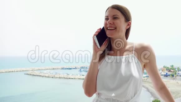 女人在阳台上用手机女性在度假时通过手机慢动作与朋友交谈视频的预览图