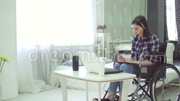 残疾青年妇女轮椅家庭远程工作电脑耳机视频的预览图