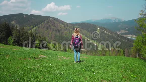 一个年轻的高加索女人带着背包和太阳镜站在山顶上举起双手概念视频的预览图