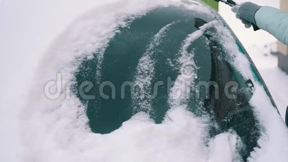 女人从汽车挡风玻璃上清除积雪视频的预览图