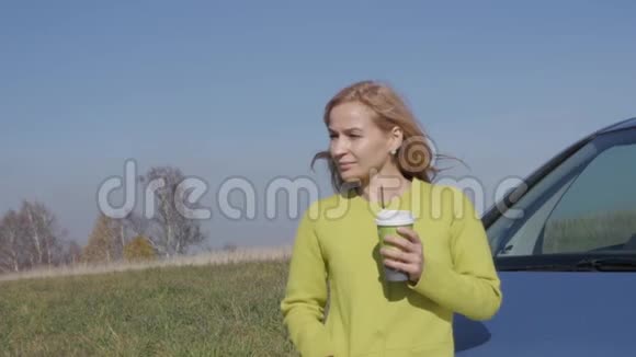 自信的年轻商务女性在农村公路上的汽车附近喝着咖啡慢动作视频的预览图
