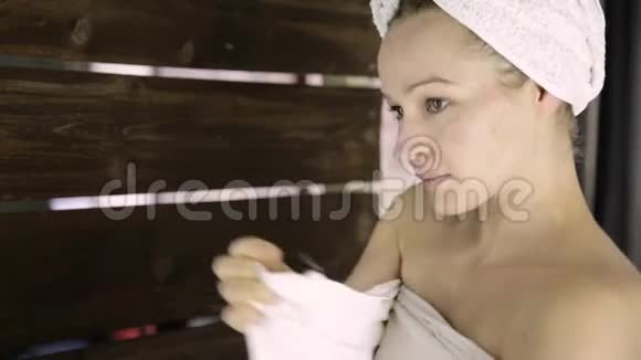 美丽的年轻女子裹着毛巾护肤和家庭水疗视频的预览图