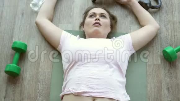 在健身俱乐部里躺在地板上筋疲力尽的胖女人视频的预览图