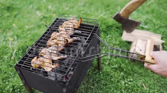 男人在烤肉上翻热熏烤鸡翅以便烤得好在后院烧烤视频的预览图