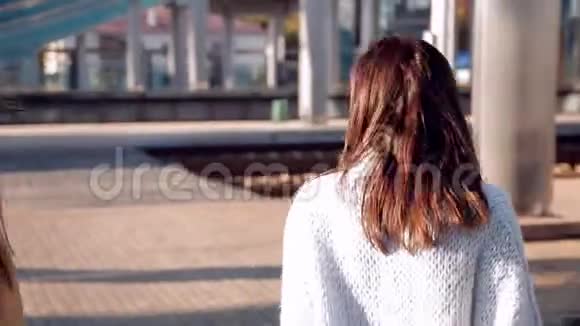 火车站的两个女孩提着手提箱站在站台上等火车视频的预览图