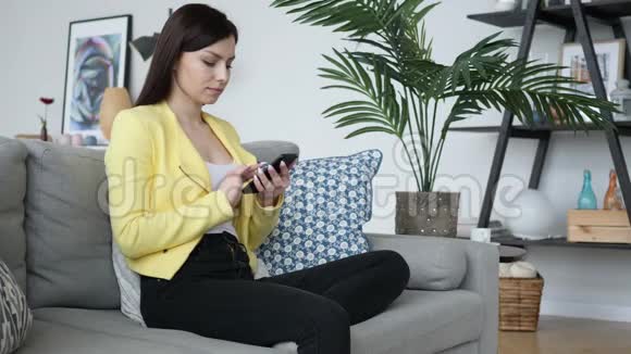 坐在沙发上用手机上网的女人视频的预览图