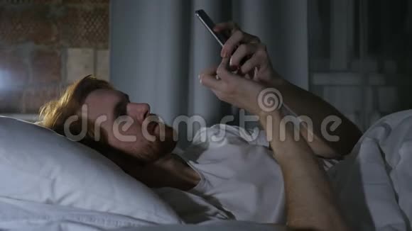 红发胡子男在床上打电话和打电话视频的预览图