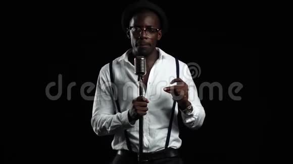 一个录音棚里的非裔美国人正在对着麦克风唱歌黑色背景慢动作视频的预览图